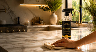 Hand wiping a polished marble kitchen countertop with Alise Edwards Multi-Purpose Cleaner nearby.